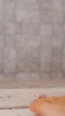 Vertical video. Close View of Woman Dropping White Dress While Entering Shower, Legs and Fabric in Focus, Low Angle, Personal Hygiene and Intimate Moment Concept