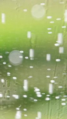 Vertical video. Slow Motion Macro View of Rising Air Bubbles in Transparent Glass with Green Background and Soft Light Reflections, Shallow Depth of Field, Refreshment Concept