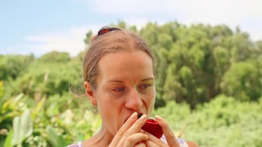 Dudaklara Yakın Kırmızı Nar Tutan ve Arka planda Yeşil Ağaçlı Meyve Yiyen Kadın, Doğal Işık, Sağlıklı Yaşam Tarzı