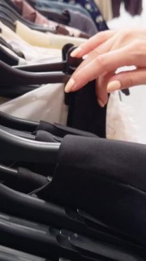 Close Up of Hands Sorting Clothes on Hangers inside Store Rack, Seen from Side Angle, Retail Shopping Concept