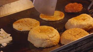 Burger Buns Pressed on Hot Griddle Beside Patties and Onions, Captured Close Up from Side Angle, Street Food Preparation Concept