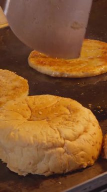 Burger Buns Pressed on Hot Griddle Beside Patties and Onions, Captured Close Up from Side Angle, Street Food Preparation Concept