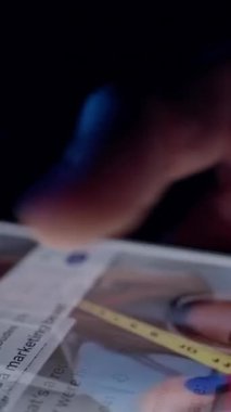 Vertical video. Hand Scrolls Social Media Feed While Slowly Pulling Smartphone Away in Red and Blue Light Emphasizing the Whole Life is in the Smartphone and Fading Real World Presence