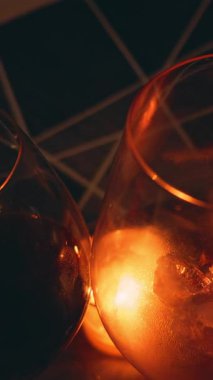 Vertical video. Bottle Pouring Red Wine into Glass Near Candlelight Creating Deep Red Glow and Warm Ambience, Romantic Celebration Concept