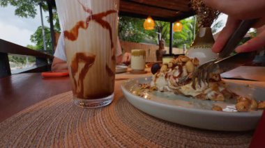 Yakın plan Elle Yeme Tatlısı Karamelli Milkshake 'in yanında çatal ve Açık Cafe' de Kahve Paylaşılan Kahvaltı ve Konsepti