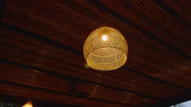 Akşam Ortamı Ahşap Tavanın Altında Asılı Örgü Bambu Lambanın Ilık Işığı, Tropikal Tasarım Konsepti ve Samimi Atmosfer