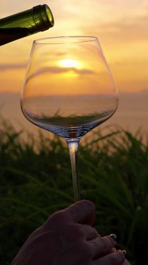 Dikey video. Sunset Sky ve Ocean View, Close Up, Romantik Gevşeme Konseptine Karşı Şarap Bardağa Dolduruluyor