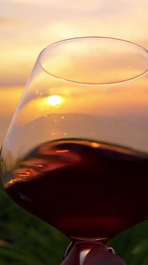 Dikey video. Ocean, Close Up, Romantik Dinginlik Konsepti yakınlarındaki Altın Gün batımında el ele tutuşan kırmızı şarap yansıtan güneş ışığı.