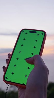 Dikey video. Sunset, Close Up, Modern Yalnızlık Konseptinde Ocean Horizon 'da Yeşil Ekran Üzerinde Yeşil Ekranlı Kadın El Tutma Akıllı Telefonu