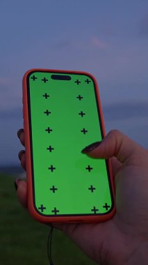 Dikey video. Dusk, Close Up, Technology and Evening calm Concept 'ta Yeşil Ekran ve Ay' da Kadın Elle Tutma Akıllı Telefonu