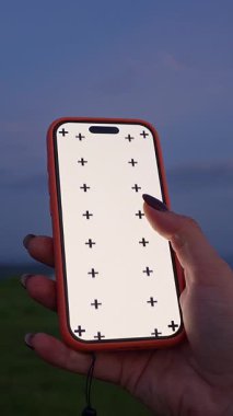 Dikey video. Beyaz Ekran ve İzleme İşaretleri Ay Işığı Gökyüzü, Yaklaş, Yeşil Ekran Arkaplanı Konsepti Altında Kadın El Tutma Akıllı Telefonu