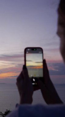 Dikey video. Smartphone, Side View, Modern Gevşeme Konsepti ile Günbatımının Fotoğrafını Çeken Kadın