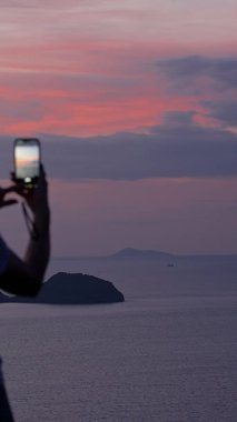 Dikey video. Hilltop, Rear View, Peaceful Technology Concept 'dan Smartphone ile Kadın Fotoğraflama Adası Günbatımı