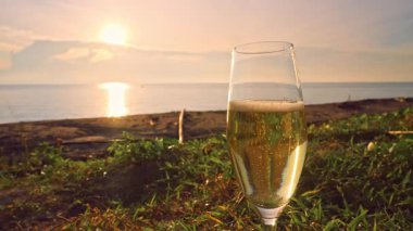 Günbatımında Tropik Plajda Duran Yükselen Baloncuklu Şampanya Kadehi Altın Sıvı ve Arkaplanda Deniz Dalgaları, Yavaş Hareket Kutlama Konsepti