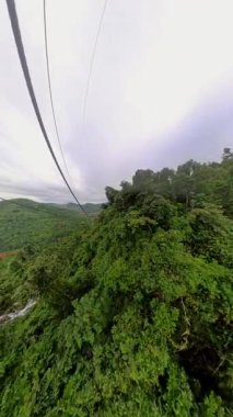Dikey video. Manzara Havacılık Konsepti sırasında yoğun yeşil gölgelik ve uzak vadilerle Cable Route Crossing Mountain Ridge boyunca tepeden görünüm