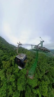 Dikey video. Cable Car Moving Upve Yoğun Orman Yukarısı Geniş Açı 'dan Bana Hills' e doğru Sahne Yolculuğu sırasında dramatik Bulutlarla Görüldü