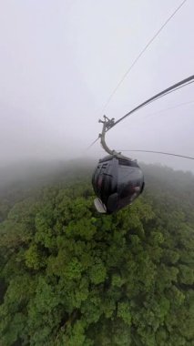 Dikey video. Bana Tepelerine Yükselirken Küçük Gezegen Efekti 'nde Sis Kaplı Ormanın Üzerinde Yüzen Kablo Arabalar