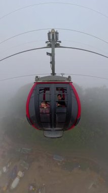 Dikey video. Ba Na Hills 'teki Kırmızı Kulübeden Dışarıya Bakan İki Kişi Geniş Açı Hava Görünümlü Yoğun Sis' te Kablo Araba