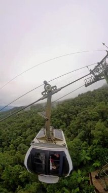 Dikey video. Geniş Açı Vuruş 'ta Ba Na Tepeleri boyunca alçak bulutlar bulunan Yoğun Orman' ın yukarısındaki Yüksek Destek Kulesi 'ne yaklaşan Kablo Arabası