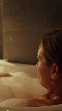 Dikey video. Küvette geriye yaslanan Kadın Sıcak Bir Yan Açı Çekimi Yumuşak bir Atmosfer Oluşturuyor