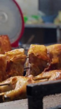 Dikey video. Yakın Açı Görünümlü Izgarada Şiş Tavuk Kızartma Altın Deri ve Sıcak Renkli Hafifletici Doku ve Sıcak Işık
