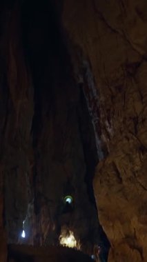 Dikey video. Altında Küçük Aydınlatma Yolu olan Büyük Dikey Mağara Duvarları Düşük Açı Görüş Alanında Dramatik Yeraltı Keşfi Sahnesi Yaratıyor