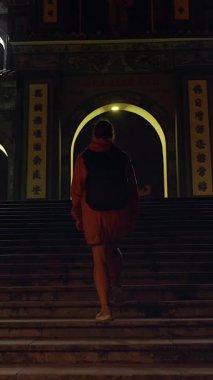 Dikey video. Gezgin Yürüyen Tapınak Adımları Gece Aydınlanmış Kapıya doğru Geniş Açı ve Simetri İfade Eden Ruhani Yolculuk Konsepti