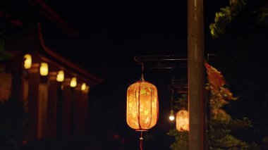 Gece Tapınak Çatısının yanında parlayan tek bir fener Sığ Derinlik ve Sıcak Ortam Işığı Kültürel Dekorasyon Konseptini ifade ediyor