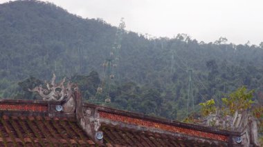 Ancient Ornamental Roof With Curved Details Overlooked by Cable Cars Ascending Forested Hill in Distant Elevated View, Cultural Landscape