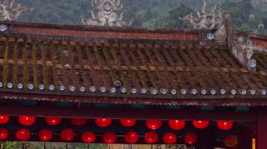 Old Tiled Roof With Moss and Red Lanterns Beneath Forested Hills and Distant Cable Cars in Soft Wide View, Cultural Atmosphere