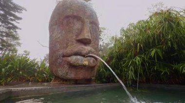 Ba Na Hills Vietnam 'da Düşük Açı Geniş Görüş Alanı' ndaki Sisli Bahçe Bitkileriyle Havuza Su Döken Büyük Taş Suratlı Çeşme, Sanatsal Kent Simgesi