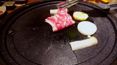 Çiğ sığır eti ince dilimleri mantar ve soğanın yanında kızarırken Tong 'lar Parlak lşık Altında Et Düzenliyor