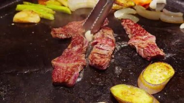 Kavrulmuş Biftek Şeritleri Kızarmış Izgaranın yanında Sebzeler Tong 'lar Yükselen Buharda Eti Kaldırırken
