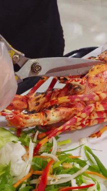 Dikey video. Eldivenli Eller Parlak Kırmızı Istakoz Kesiyor Beyaz Tabakta Makas ve Taze Sebzeler Deniz Ürünleri Mutfağı Mutfağı Konseptinde