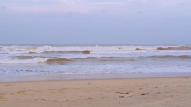 Geniş Açı Yavaş Görünüm Sert Deniz Dalgaları Yumuşak Şafak Gökyüzü altında Sessiz Kum Kıyı 'ya doğru yuvarlanırken bir sakinlik kavramı yaratıyor