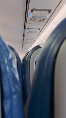 Dikey video. Düşük Açı İç Görünümü: Uçak Koltukları ve Mavi Işıklar Parlak Kabinde Bir Uçak İç Konsepti Oluşturma Paneli