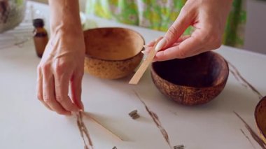 Coconut Bowl in Soft Overhead Light 'ın üzerinde tahta bir çalı tutarken DIY Mum Hazırlama Başlıyor, Doğal Zanaat