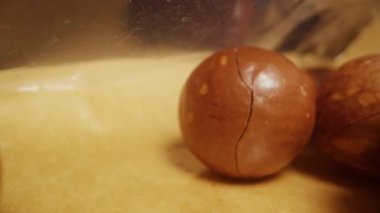 Glossy Surface 'de Metal Bıçak Kesme Kabuğuyla Macadamia Fındıklarını Kapat, Gıda Hazırlama Süreci, Fındık Kırma Eylemi, Mutfak Malzemeleri Tutuşu, Sağlıklı Atıştırma Konsepti