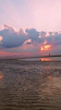 Geniş Açı Hızlı İnsansız Hava Aracı Uçan Kadın 'a doğru Uçuyor Geniş Islak Kumsalda Duruyor ve dramatik Bulutlar ve Güçlü Hareket Etkisi, Dinamik Seyahat Konsepti ile Parlak Orange Sunset' te yanından geçiyor