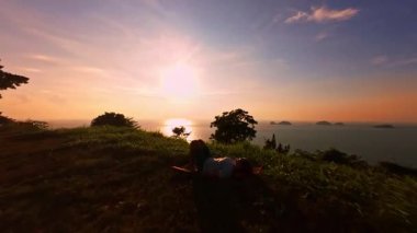 Yavaş İnsansız Hava Aracı Uçağı Çimenlerin Üzerinde Uzanıyor ve Sakin Deniz Üzerinde Parlak Altın Gün Batımına İlerliyor Sıcak Işık ve Huzurlu Kıyı Ufkusu, Derin Gevşeme Kavramı