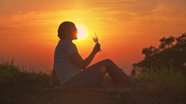 Geniş Çekim Kadın Tepede Oturuyor Köpüklü Şarap İçiyor Geniş Altın Gün batımına karşı Horizon Denizi, Özgürlük Konsepti