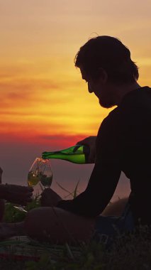 Dikey video. Sunset Piknik, Yavaş Rahatlatılmış Kutlama Sahnesi 'nde Kadın İçin Şampanyayı İçen Adam' ın Yakın Çekimi