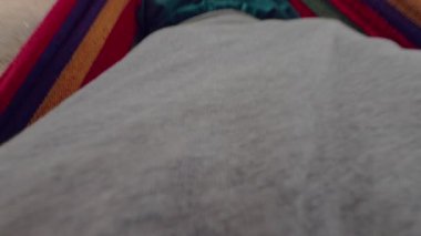 Sahilin yakınındaki renkli bir hamakta yatan bir adam Lush Trees, Palm Trunks ve sakin bir sahil şeridi ile birinci şahıs tarafından gösterilen rahat bir Tropik Kaçış yaratıyor.