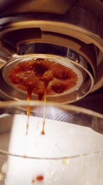 Dikey video. Yavaş Çekim Ekstrem Espresso Kapanışı Dipsiz Portafilter 'dan patlıyor Kaotik kahve akıntıları ve Kaplama Makinesi ve Kupa Patlamasını Gösteriyor