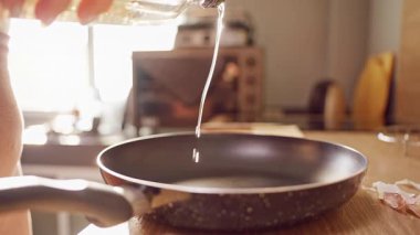 Yavaşça yağın şişeden tavaya dökülmesi mutfak tezgahında sıcaklıkla yemek pişirmeye hazırlanması.