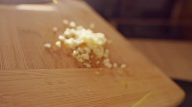 Doğranmış sarımsağın, yağlı tavayı kızartma süreciyle kesme tahtasından, aşçılık sürecini ve bileşen transferini gösteren tavaya kaydırma işleminin yavaşlığı