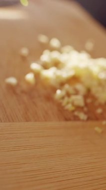 Dikey video. Doğranmış sarımsağın, yağlı tavayı kızartma süreciyle kesme tahtasından, aşçılık sürecini ve bileşen transferini gösteren tavaya kaydırma işleminin yavaşlığı