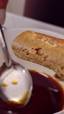 Dikey video. Savoiardi Bisküvisi 'nin üstüne kadın eli dökülen kahvenin kapanışı, Tiramisu Tatlıları Hazırlığı sırasında Bisküvi özümseme Sıvısı