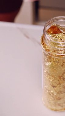 Dikey video. Tiramisu Tatlısını Süslemek İçin Cımbızla Konteynırdan İnce Altın Yaprağın Çıkarılmasının Kapanışı