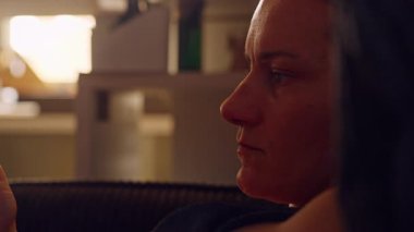 Ciddi Yetişkin Kadın Düşük Işık, Duygusal Odaklanma ve Dijital Yansıma Anında Akıllı Telefon Ekranına Bakıyor